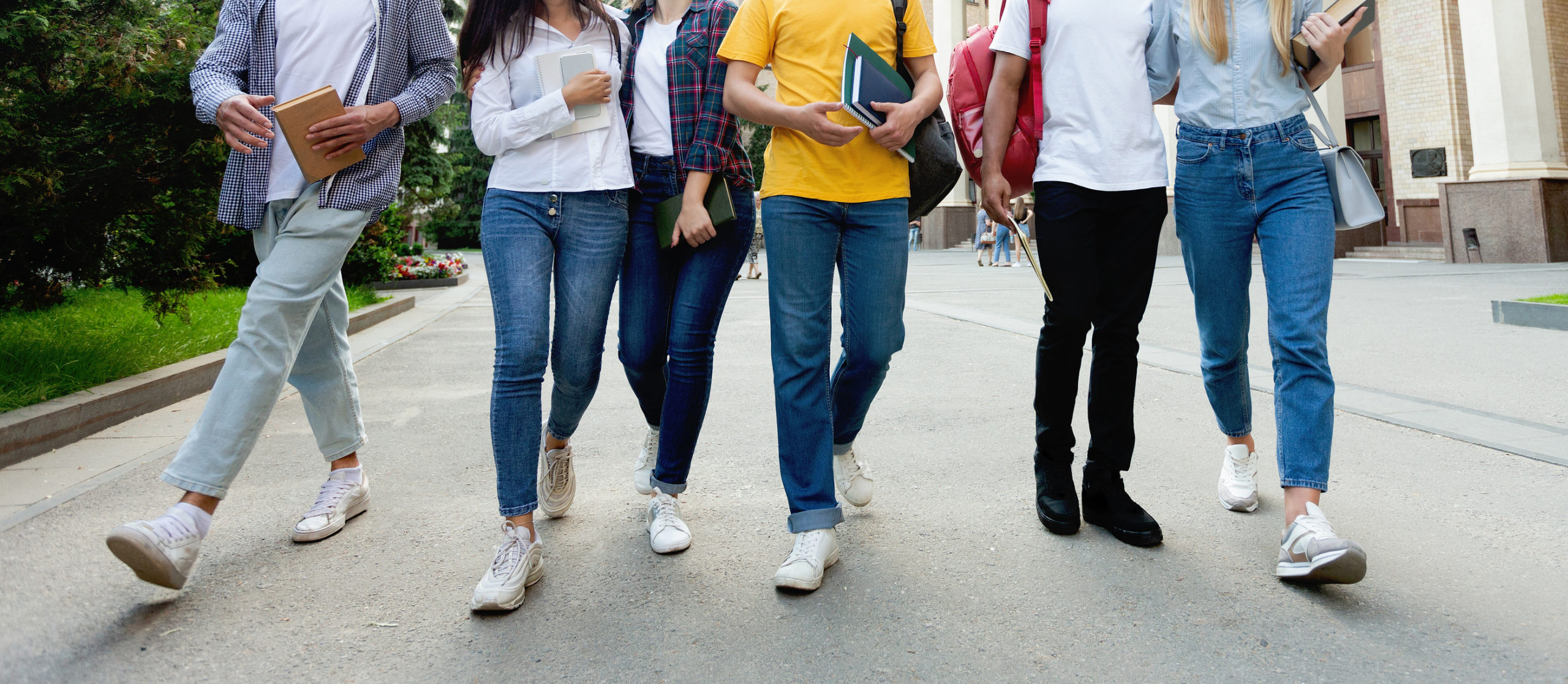 College students in high school campus walking during break, focus on legs, crop